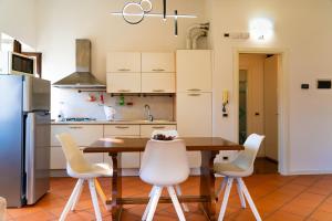 eine Küche mit einem Holztisch und weißen Stühlen in der Unterkunft Casa Marilyn in Desenzano del Garda