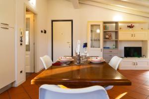 ein Esszimmer mit einem Holztisch und weißen Stühlen in der Unterkunft Casa Marilyn in Desenzano del Garda