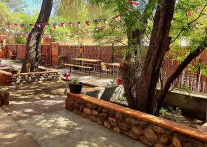 a garden with a table and a tree and a fence at Hostal Perita in San Pedro de Atacama