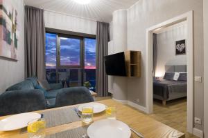 ein Wohnzimmer mit einem Tisch, einem Sofa und einem Bett in der Unterkunft HANZA TOWER HIGH FLOOR Swimming Pool & Spa in Stettin