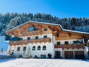 a building in the snow with trees in the background at Hubertus - Das Landhaus in Kleinarl