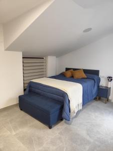 a bedroom with a bed and a blue ottoman at Raíces de Alcalá in Alcalá del Júcar