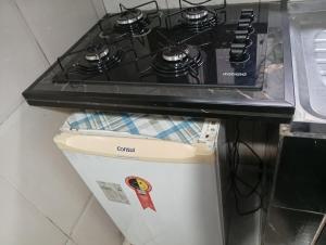 a stove top oven sitting on top of a refrigerator at CASAS e KITNETS NOSSO CANTINHO in Barra do Sahy