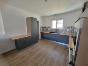 an empty kitchen with blue cabinets and a window at Jolie T4 rénové avec balcon-terrasse in Argeliers