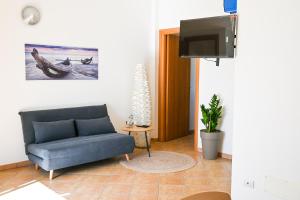 a living room with a couch and a flat screen tv at Casa Azul - Social Apartment - parcheggio, clima, 200mt dal mare in Scoglitti