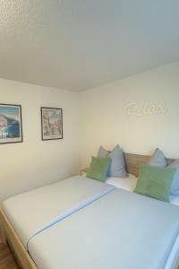 een slaapkamer met een wit bed met groene kussens bij FeWo Im Drosselnest in Hechingen