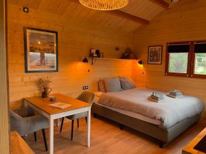 a bedroom with a bed and a table in it at Mas des Poutres - Tiny house in Charmes-sur-lʼHerbasse +28 photos