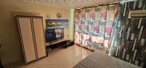a room with a television and a wall with curtains at Курортно студио in Sunny Beach