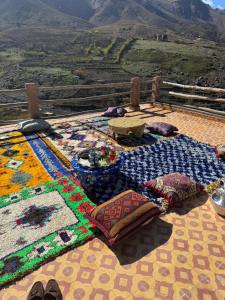 a table with blankets and pillows on top of a mountain at Dar Agourzi Café des Epices in Tacheddirt