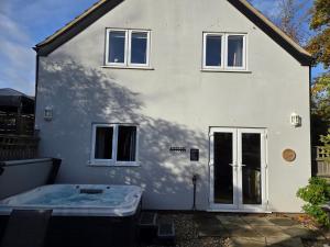 a white house with a tub in front of it at Farthing Cottage in Norwich