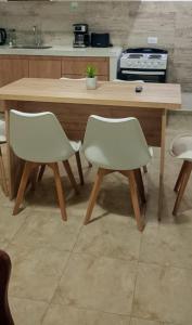 a kitchen with a wooden table and two white chairs at Duplex Atenea in Chivilcoy