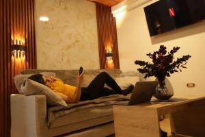 a woman laying on a couch looking at her cell phone at INTI & QUILLA Appartments in Sibundoy +8 photos