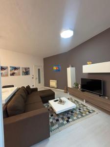 a living room with a brown couch and a tv at Green Hill Tirana Apartment in Selitë e Vogël