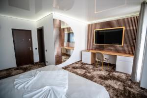 a bedroom with a bed and a desk with a television at Fit Residence Hasdeu in Cluj-Napoca