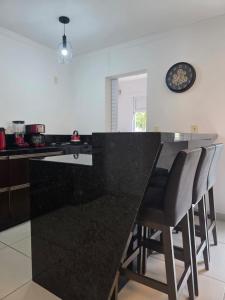 a kitchen with a black counter top and bar chairs at Apartamento Artzoo in Pomerode