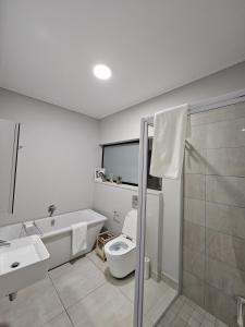 a bathroom with a toilet and a sink and a shower at CostaBella in Gqeberha +8 photos