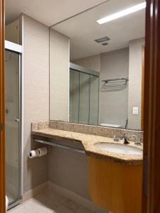 łazienka z umywalką i dużym lustrem w obiekcie Suíte Particular no Transamerica Executive Faria Lima w São Paulo