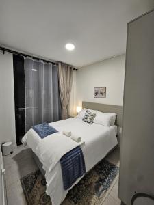 a bedroom with a large white bed and a window at CostaBella in Gqeberha