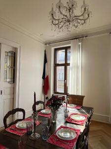 een eetkamer met een tafel met een kroonluchter bij Apparemment de style 70s in Colmar