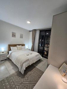 a bedroom with a large white bed and a window at CostaBella in Gqeberha