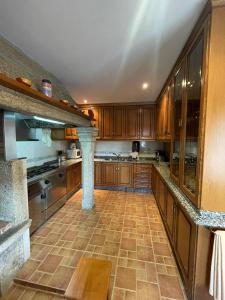 a large kitchen with wooden cabinets and a stone pillar at Casa Os Batáns in Vimianzo +53 photos