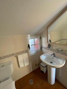 een badkamer met een wastafel, een toilet en een spiegel bij Casa Os Batáns in Vimianzo