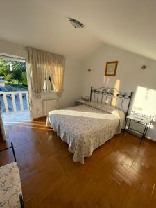 een slaapkamer met een bed en een houten vloer bij Casa Os Batáns in Vimianzo