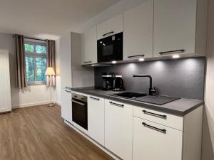 a kitchen with white cabinets and a sink at Business Apartments - Hof Wanstrath - select2stay in Badbergen