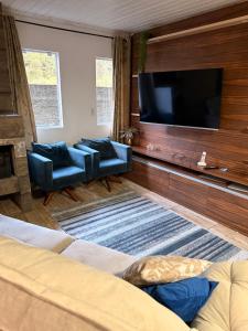 Una sala de estar con un televisor de pantalla plana en una pared. en Casa no centro de Urubici Dutra Borba, en Urubici