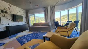 ein Wohnzimmer mit einem Sofa, einem TV und Stühlen in der Unterkunft Apartament Słoneczny z aneksem Biała Perła Czarna Góra in Heudorf