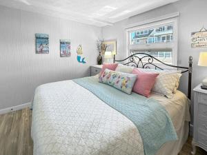 a bedroom with a bed with pink and blue pillows at Admiral's Quarters in Wells Beach