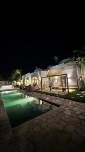 una piscina frente a una casa por la noche en Casa Dea - bungalow Mykonos, en Hammamet Sud