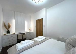 a white bedroom with two white beds and a desk at Cosy Hideaway in Stirling