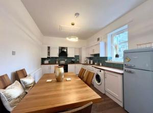 a kitchen with a wooden table and a refrigerator at Cosy Hideaway in Stirling
