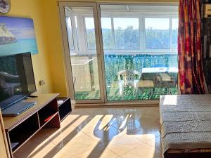 a living room with a large window and a television at Курортно студио in Sunny Beach