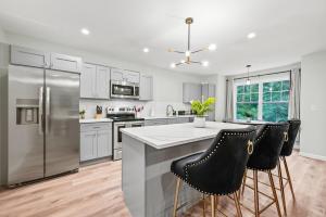 a kitchen with a stainless steel refrigerator and bar stools at Ideal Family Stay Sleeps 20 in Bloomfield CT in Bloomfield