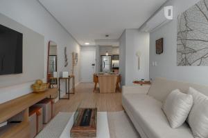 a living room with a white couch and a tv at Residencial Lumiére 2 dorm by Achei in Canela