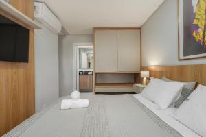 a bedroom with a large white bed with a flat screen tv at Residencial Lumiére 2 dorm by Achei in Canela
