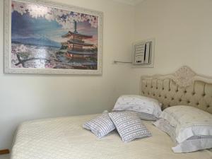 a bed with two pillows and a painting on the wall at Apartamento Caioba in Matinhos