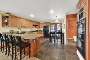 a kitchen with wooden cabinets and a black refrigerator at Eden Mountain Condo with Views Pool & Hot Tub Access in Wolf Creek Village