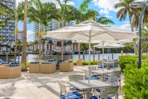 an outdoor patio with tables and chairs and umbrellas at GALLERY One - A DoubleTree Suites by Hilton Hotel in Fort Lauderdale