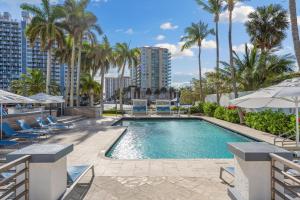 a swimming pool with chairs and palm trees at GALLERY One - A DoubleTree Suites by Hilton Hotel in Fort Lauderdale
