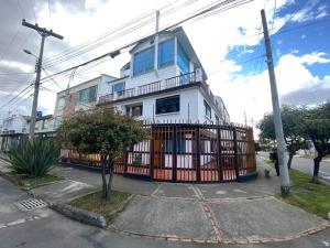 a white house with a gate in front of it at casabosque habitacion301 in Bogotá