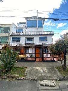 a white house with a fence in front of it at casabosque habitacion301 in Bogotá