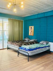 two beds in a room with a blue wall at Villa Palma in Tbilisi City