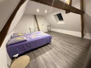 a bedroom with a purple bed and a wooden floor at Maison de Lili - Spacieuse in Beynat