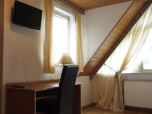 a room with a desk and a television and a window at Hotel Haus Niggemann in Hattingen