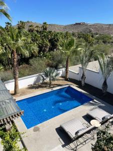 een zwembad met stoelen en palmbomen bij Gorgeous Downtown 4BR House with Pool, Jacuzzi & Firepit in Todos Santos