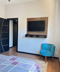 a living room with a tv and a blue chair at Flat Funcional Moderno | Conforto e Praticidade in Nova Friburgo