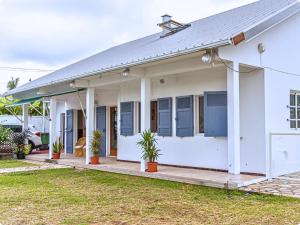 a white house with blue shutters and potted plants at Le Mohana - L'évasion tropicale de l'Est in Saint-André